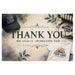 A promotional mockup showing several apparel items with placeholder branding: a navy baseball cap, a white T-shirt, and a round plate, all printed with generic 'YOUR LOGO' text and mountain graphics. The center contains large decorative text reading 'THANK YOU WE REALLY APPRECIATE YOU' over a textured beige background with floral and ornamental accents.